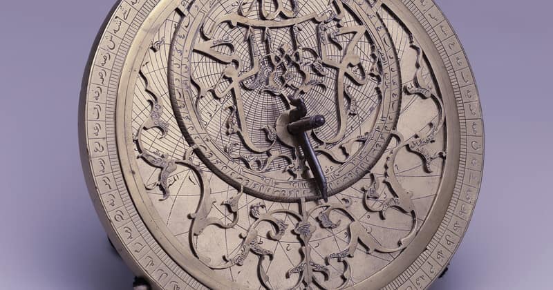 An engraved brass astrolabe, its rings and pointers catching the light