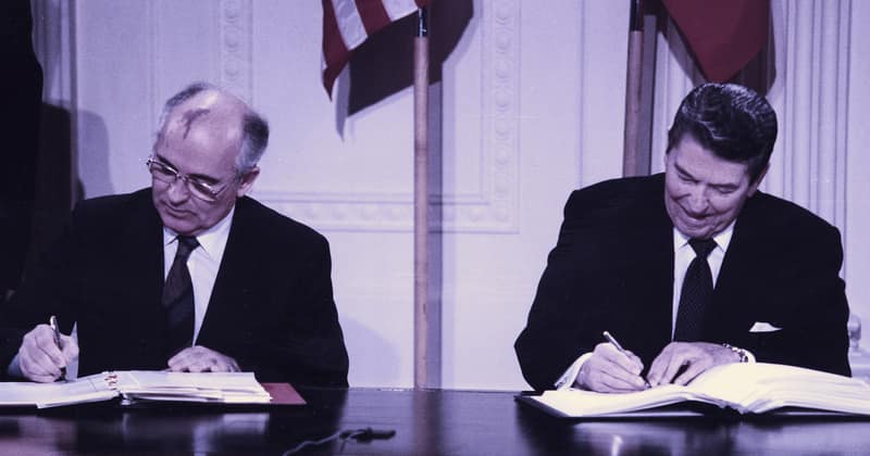 Ronald Reagan and Mikhail Gorbachev seated at a desk in the East Room of the White House, signing the INF Treaty